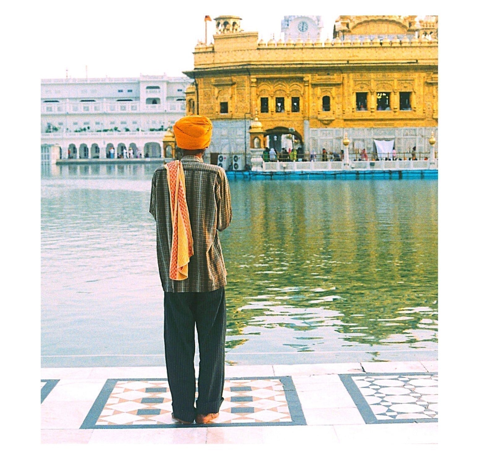 man wearing orange turban standing near water at Golden Temple India with reflection calm water interesting amazing facts India