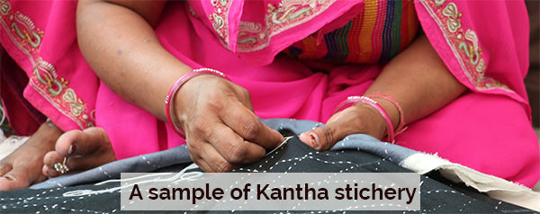 Close-up of hands stitching Kantha embroidery on fabric in traditional Indian attire