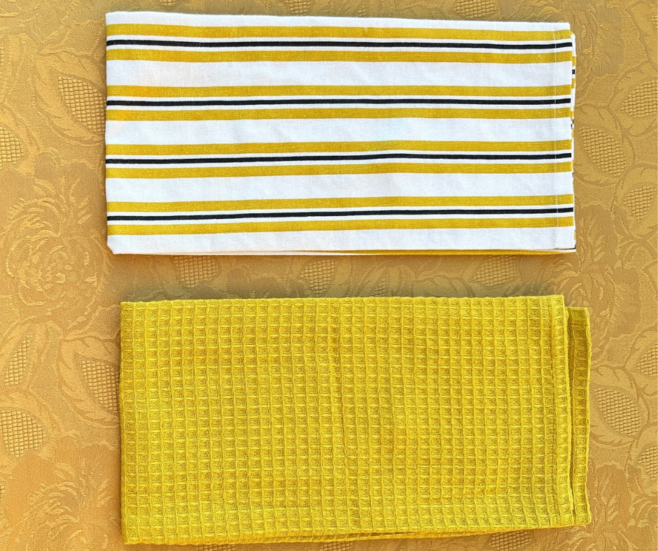 Yellow and white striped cotton table linen and solid yellow textured cloth on a mustard floral-patterned background