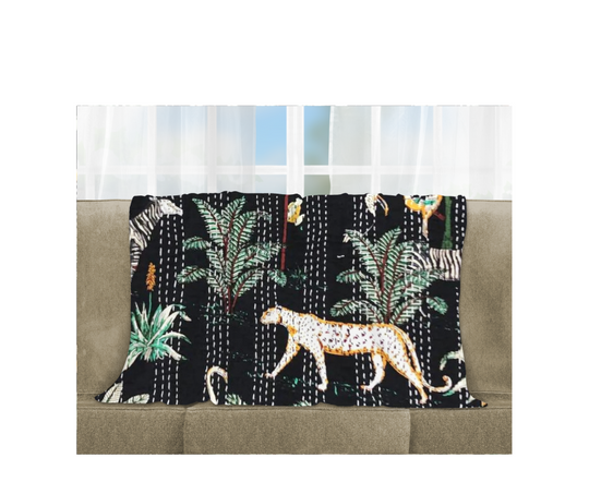 Kantha Blanket Safari with hand-stitched animal and plant patterns on black cotton voile, lightweight and quilted, draped on sofa.