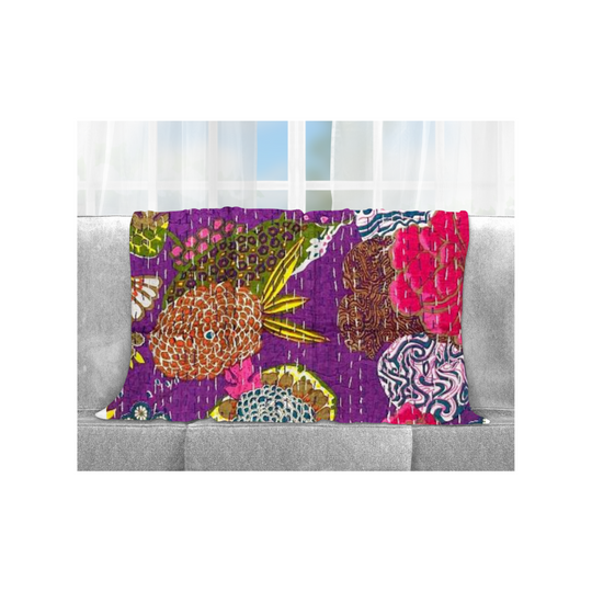 Colorful handmade Kantha Blanket with tropical floral patterns draped over gray sofa, lightweight cotton quilt with traditional stitching.